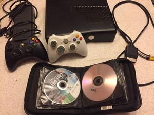 Xbox 360 slim con controles y juegos.