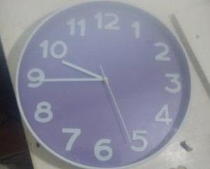 Reloj de pared blanco con fondo lila. Funciona perfecto
