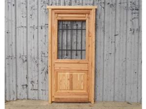 Puerta de frente en madera antigua de pinotea con reja