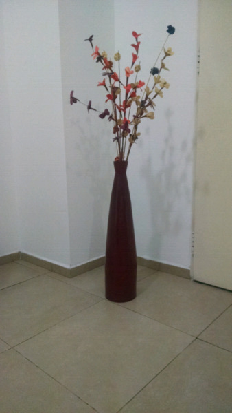 Florero decorativo de color rojo oscuro con flores pa living